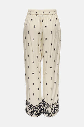 Ecru broek van JDY met kleine bladmotieven en brede bloemenrand op de broekspijpen.