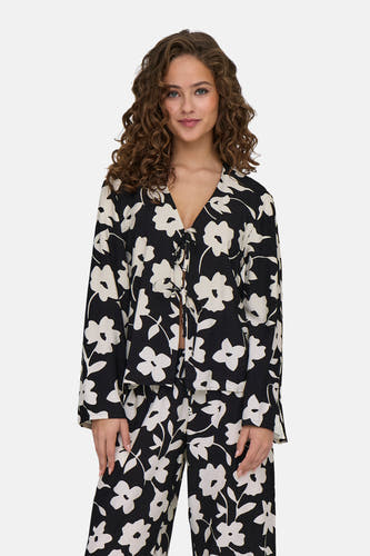 Blouse noire à manches longues de JDY, avec un motif floral, associée à une jupe coordonnée et des chaussures blanches.