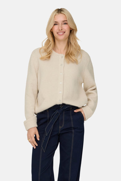 Ecru cardigan van ONLY, met knoopsluiting en lange mouwen, gedragen met een donkerblauwe broek.
