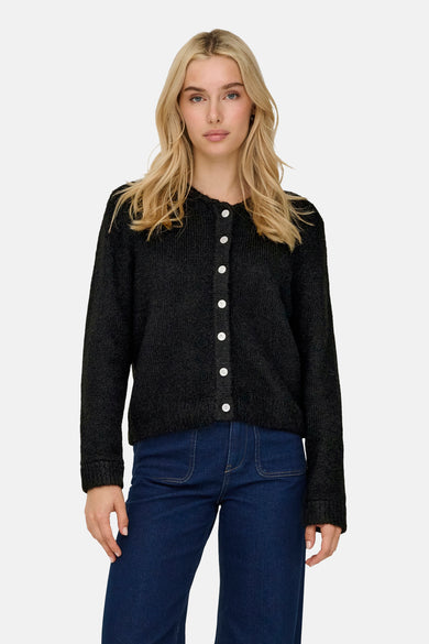Zwarte cardigan van ONLY, met lange mouwen en witte knopen, gecombineerd met donkerblauwe jeans.
