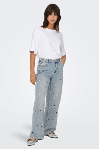Lichtblauwe wijde jeans van ONLY, met gaten versierd en gedragen met een wit T-shirt en zilveren schoenen.
