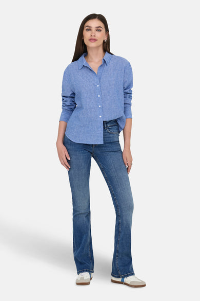 Middenblauwe denim flared jeans van JDY, gedragen met een gestreept blauw overhemd en witte sneakers.

