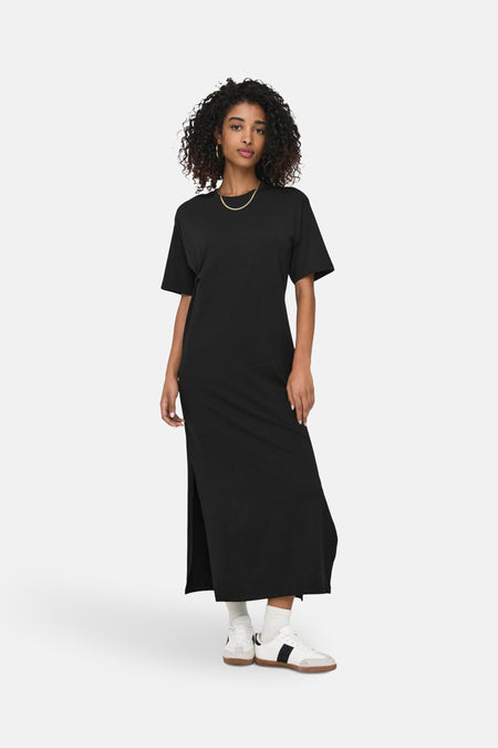 Zwarte jurk met korte mouwen van ONLY, met zijsplit en gecombineerd met witte sokken en sneakers.
