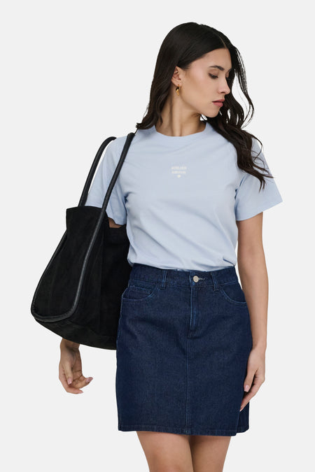T-shirt bleu de JDY, à manches courtes et avec un petit imprimé, combiné avec une jupe en jean et un sac noir.