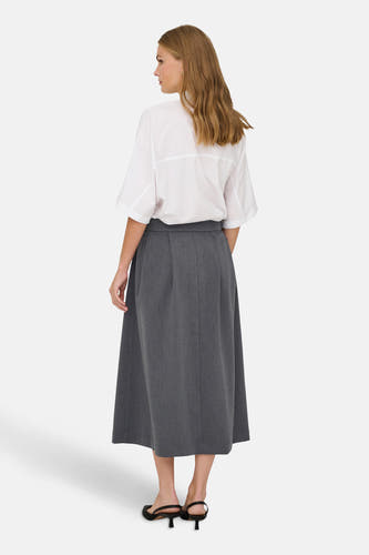 Jupe grise de JDY, avec des plis et une longueur midi, associée à une blouse blanche.