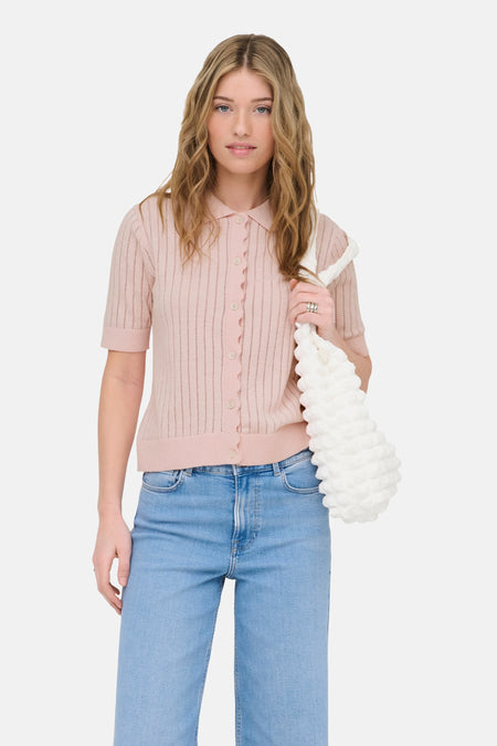 Gilet rose de ONLY®, à manches courtes et fermeture boutonnée, combiné avec un jean et des escarpins blancs.
