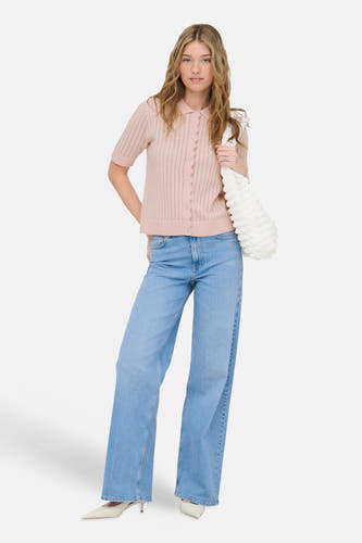 Roze vest van ONLY®, met korte mouwen en een knoopsluiting, gecombineerd met een spijkerbroek en witte pumps.

