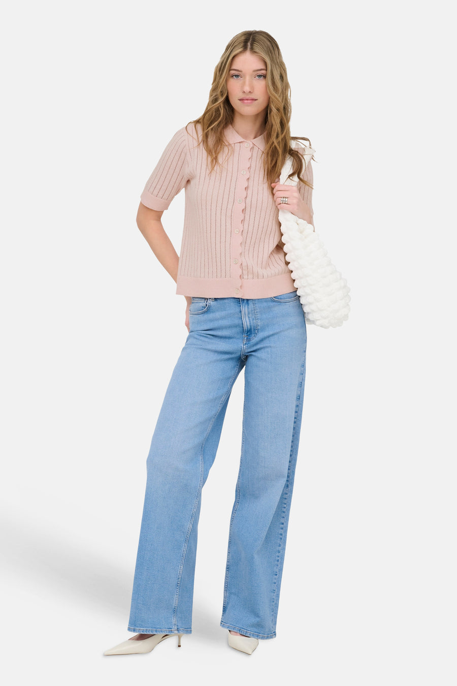 Roze vest van ONLY®, met korte mouwen en een knoopsluiting, gecombineerd met een spijkerbroek en witte pumps.
