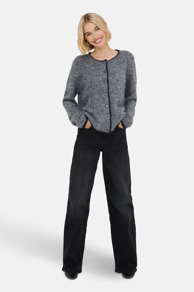 Gilet gris de JDY, porté avec un pantalon noir à larges poches et les mains dans les poches.