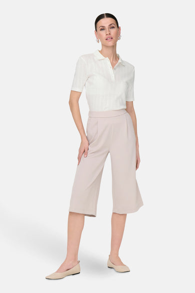 Witte polo met korte mouwen van JDY, met knoopsluiting en gedragen met beige culotte en platte schoenen.
