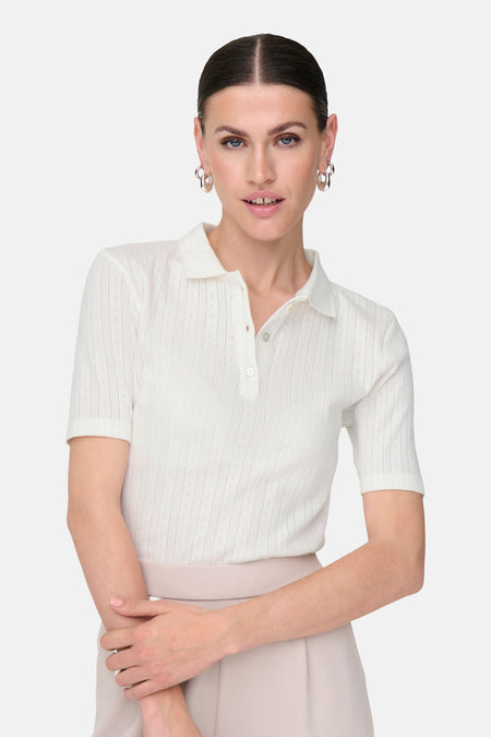 Witte polo met korte mouwen van JDY, met een fijne structuur en gedragen met zilveren oorbellen.

