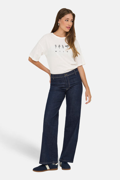 Donkerblauwe straight jeans van JDY, gecombineerd met een wit T-shirt met print en blauwe sneakers.
