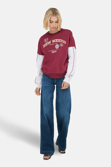 Gilet de Bordeaux ONLY®, avec logo New Mexico et manches grises longues, associé à des jeans larges et des sandales noires.