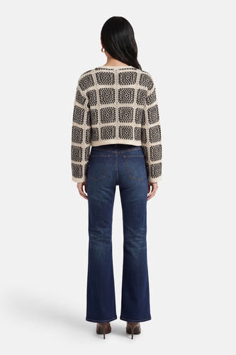 Multikleurig vest van ONLY®, met een zwart-wit geometrisch patroon, gecombineerd met donkerblauwe jeans en bruine hakken, achteraanzicht.
