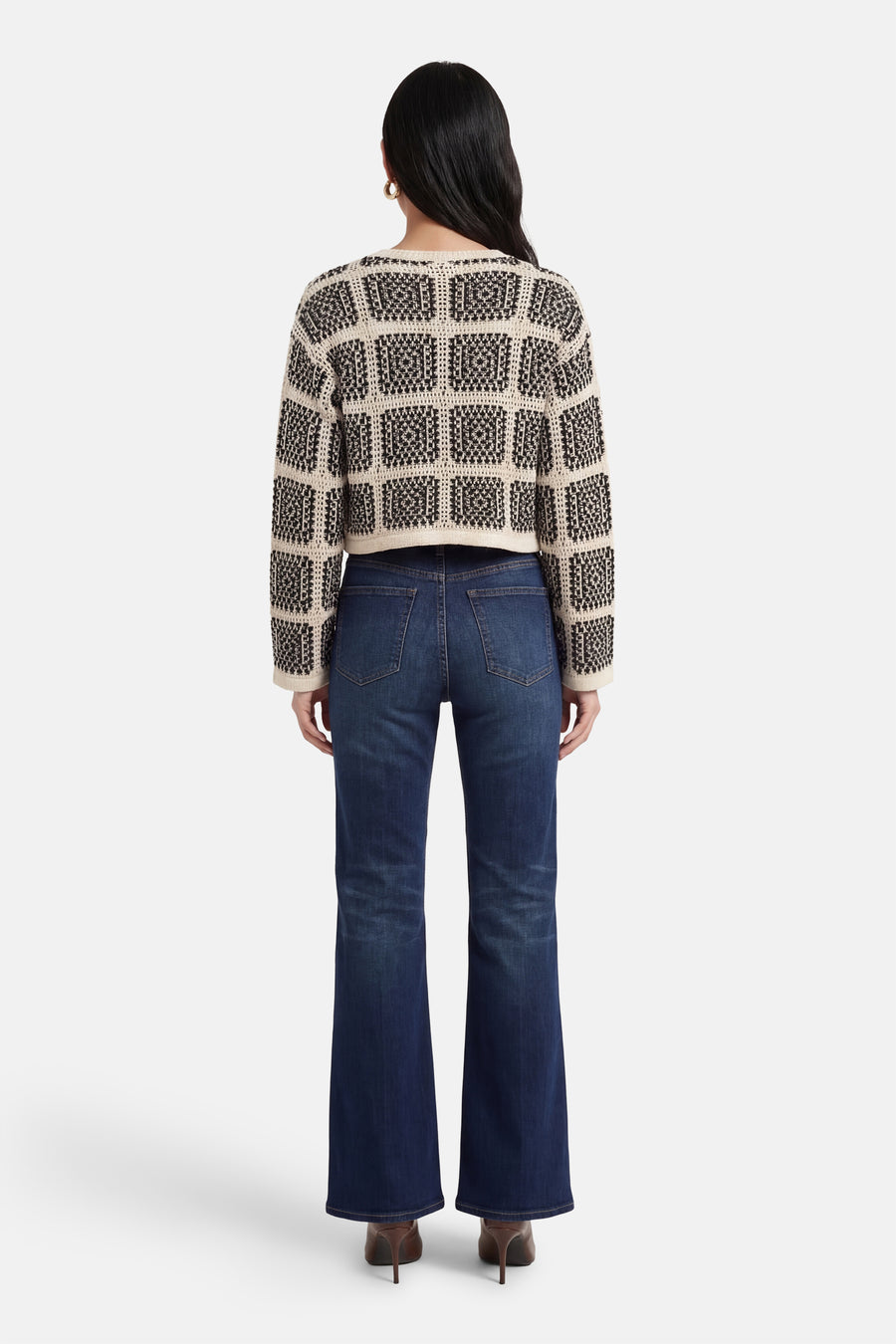 Multikleurig vest van ONLY®, met een zwart-wit geometrisch patroon, gecombineerd met donkerblauwe jeans en bruine hakken, achteraanzicht.
