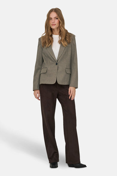 Bruine blazer van JDY, met een enkele knoopsluiting en opgestikte zakken, gedragen over een wit shirt met donkerbruine pantalon.
