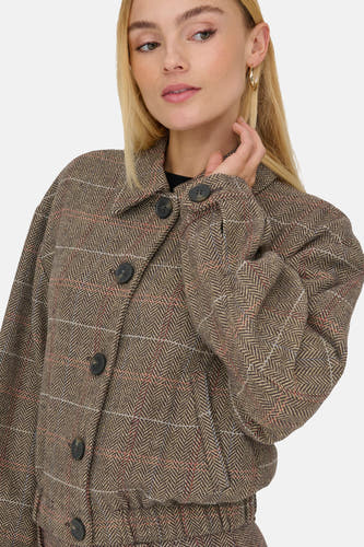 Bruine jas van ONLY®, met een visgraatmotief en knoopsluiting, gedragen door een blond model.