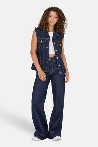 Donkerblauw denim vest van ONLY, met zilveren knopen, gedragen over een wit topje en donkerblauwe wijde pijpen jeans.
