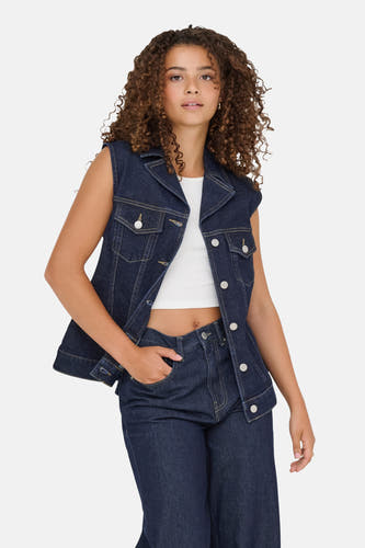 Mouwloze jas van donkerblauw denim van ONLY, gedragen over een witte top en bijpassende jeans.
