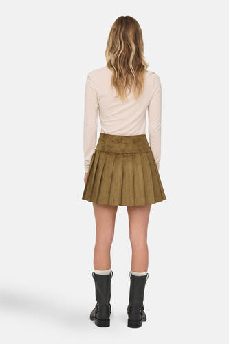Jupe courte brune de ONLY®, avec des plis, portée avec des bottes noires et un chemise crème, dos.