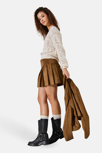 Jupe courte brune d'ONLY, plissée, portée avec une chemise crème, des chaussettes et des bottes noires.