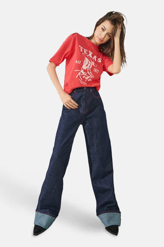 Donkerblauwe wide jeans van ONLY, met rode stiksels, gecombineerd met een rood T-shirt met opdruk.