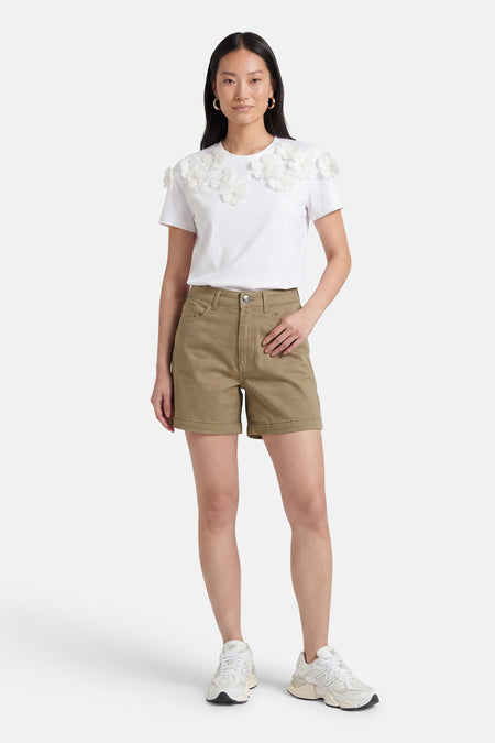Beige korte broek van ONLY® met gerolde zoom en klassieke vorm, gedragen met witte bloemen t-shirt en sneakers, front view