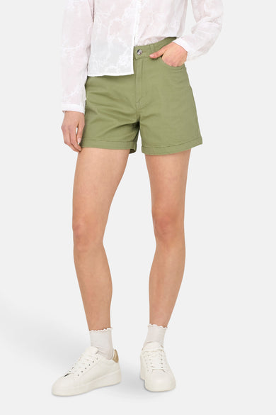 Short vert de ONLY, combiné avec une blouse blanche et des baskets blanches à des accents dorés.