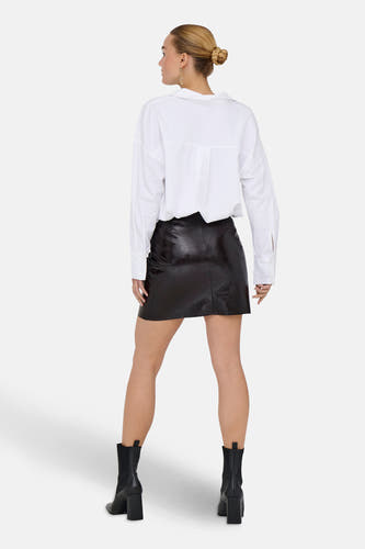 Jupe courte brune de JDY portée avec une chemise blanche et des bottes noires, vue de derrière.