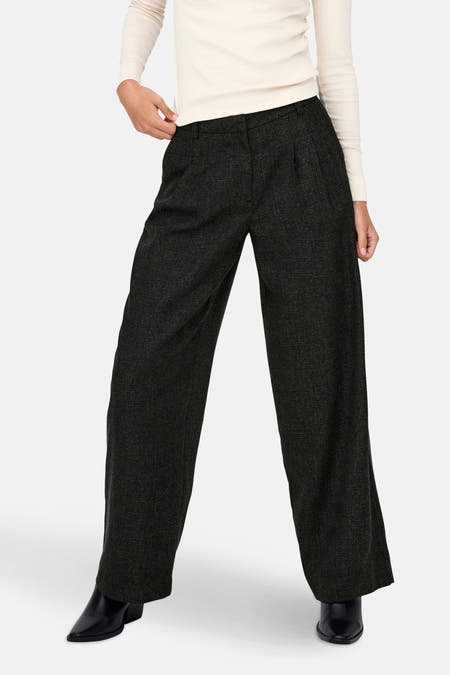 Grijze broek van JDY met wijde pijpen en zwarte schoenen.
