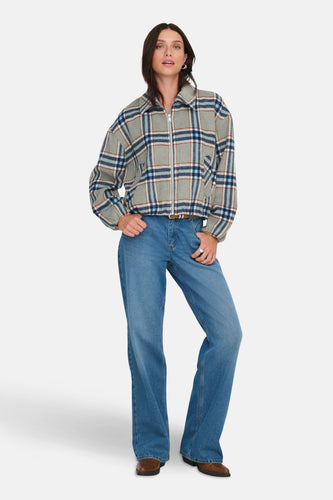 Multikleurige korte jas van ONLY, met een ruitpatroon en gecombineerd met blauwe jeans en bruine laarzen.
