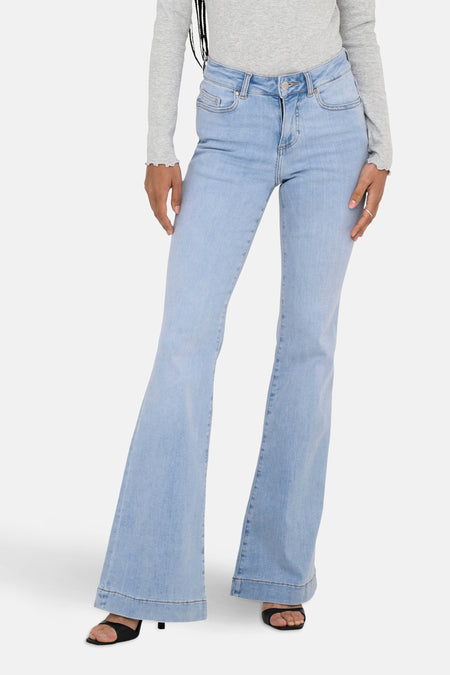 Lichtblauwe flared jeans van ONLY, met een grijze top met lange mouwen en zwarte hakken.
