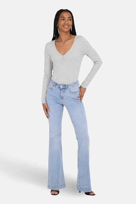 Lichtblauwe flared jeans van ONLY, met een grijze top en zwarte sandalen.
