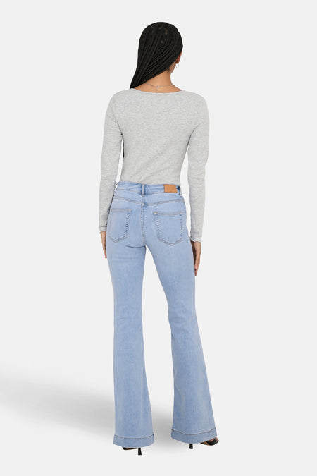 Jean flare bleu clair ONLY, vu de l'arrière combin combiné avec un chemisier gris à longues manches et des chaussures noires à talons.