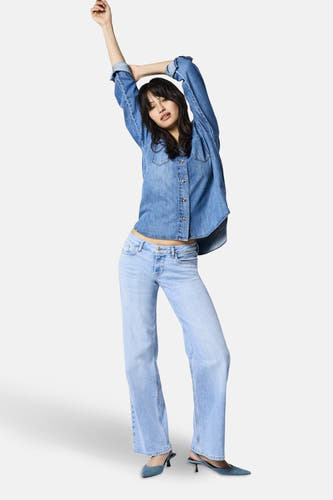 Jean en denim bleu clair large d'ONLY, avec une taille haute et associé à un pull beige.