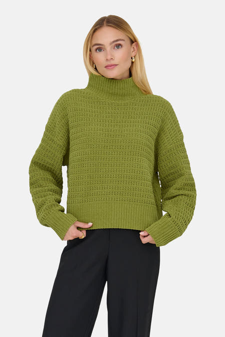 Groene coltrui van ONLY, met grove gebreide textuur gedragen over een zwarte pantalon.
