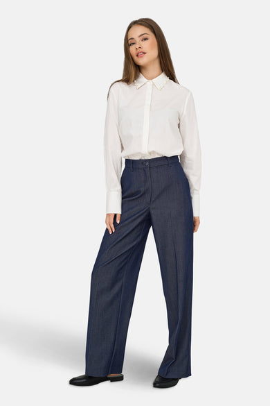 Jeanonau bleau de JDY, porté avec une blouse blanche à col en perles et des chaussures noires.