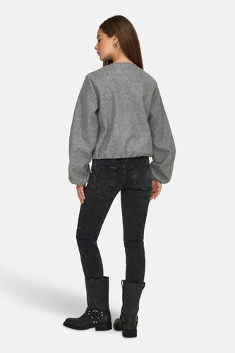 Grijze korte jas van JDY, gezien van achteren, met zwarte jeans en zwarte laarzen.