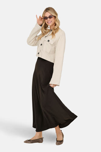 Lange bruine rok van JDY, gedragen met een beige jack en bruine ballerina's.