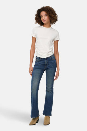 Donkerblauwe flared jeans van JDY, gecombineerd met een wit T-shirt en suède laarsjes.