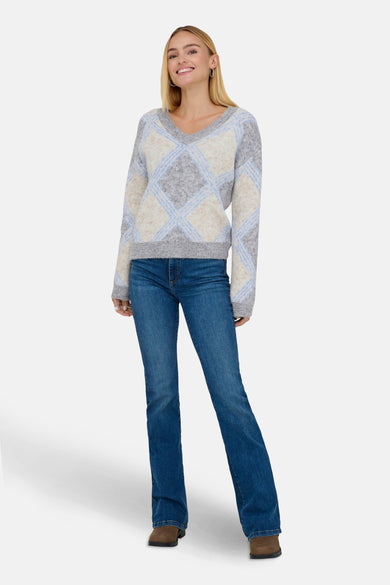 Een vrouw in een geruite trui, jeans en bruine schoenen.