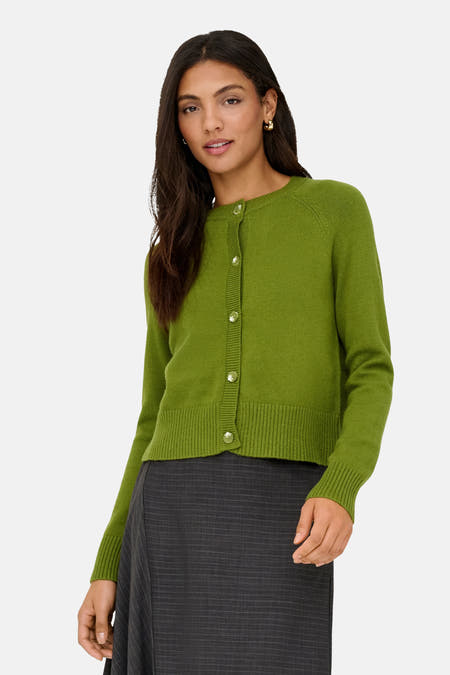 Groene cardigan van ONLY® met lange mouwen en knoopsluiting, gedragen met een grijze rok met krijtstrepen.
