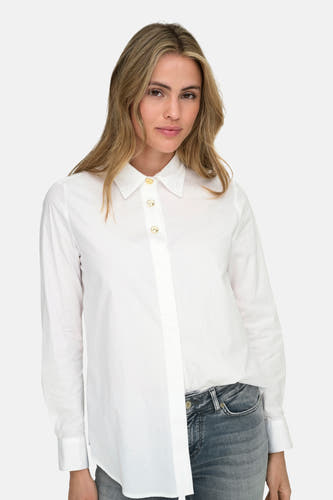 Chemise blanche à longues manches de ONLY, avec des boutons dorés et portée avec un jean.