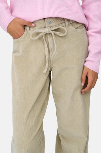 Pantalon écru de ONLY, avec un détail noué et une texture corduroy, associé à une chemise rose.