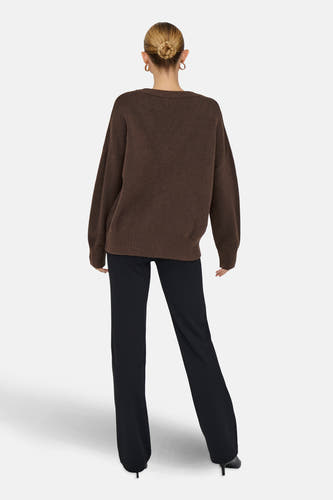 Bruine V-hals trui van ONLY, gedragen met zwarte broek en hakken, achterkantweergave.
