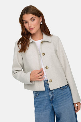 Manteau court écru d'ONLY, avec une fermeture à boutons et porté sur un T-shirt blanc et des jeans bleus.