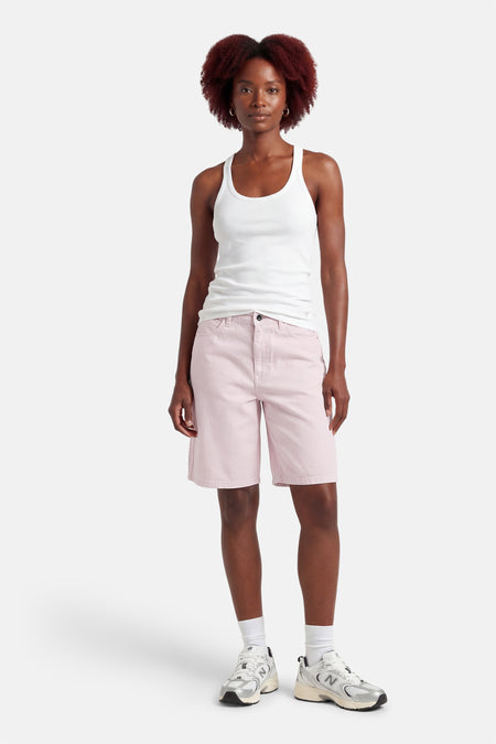Roze short van ONLY, gedragen met een witte tanktop en witte sokken met zilveren sneakers.