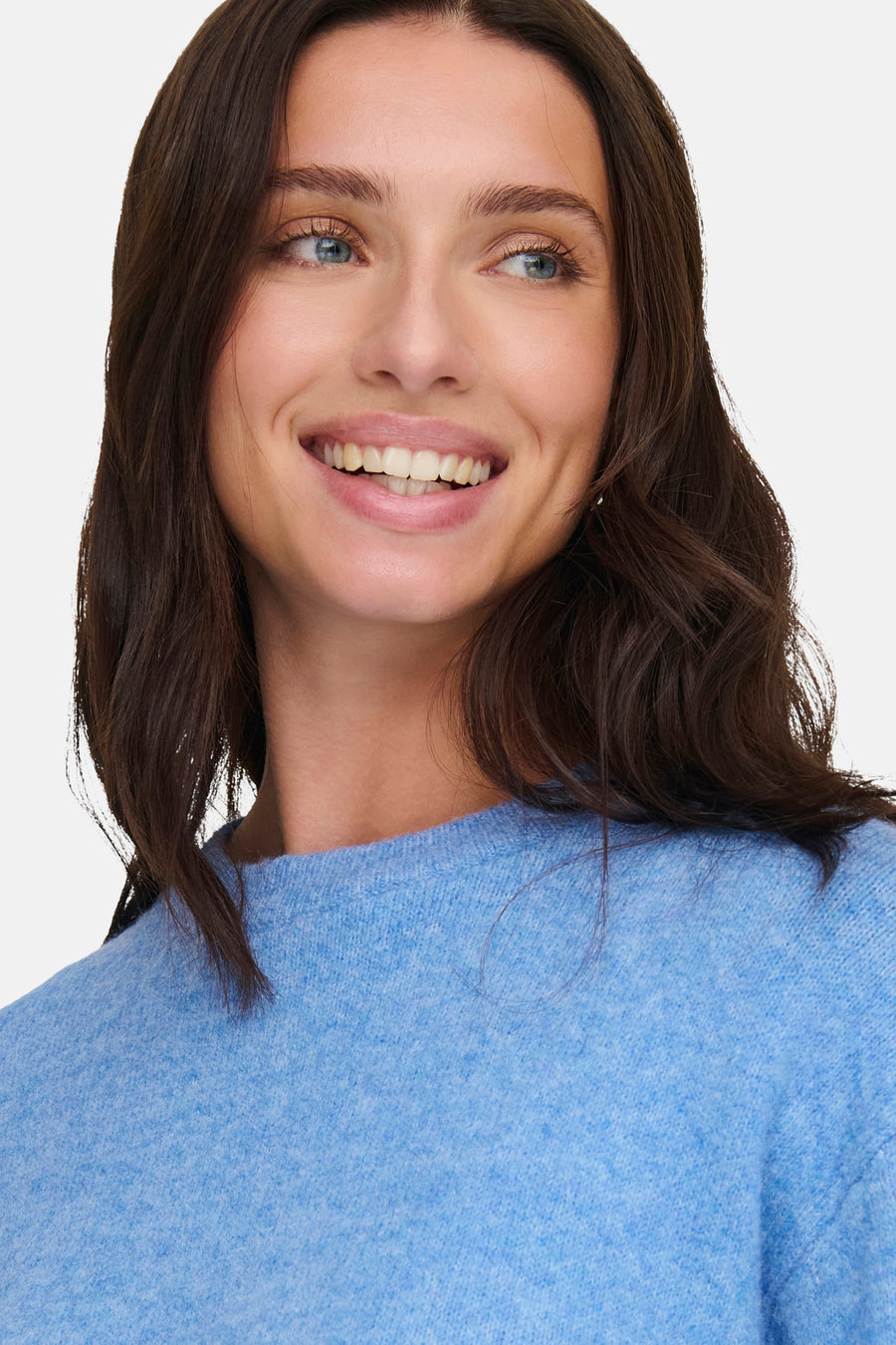 Blauwe trui met ronde hals van JDY, close-up van model met donkerbruin haar en blauwe ogen.
