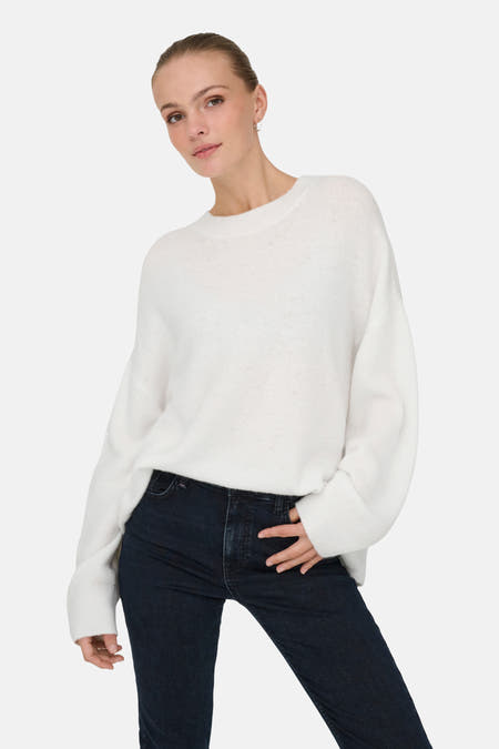 Witte trui met ronde hals van JDY, gecombineerd met donkere jeans.
