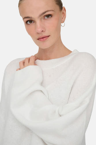 Pull-over blanc avec col rond de JDY, avec une main sur la patte et des boucles d'oreilles en argent.